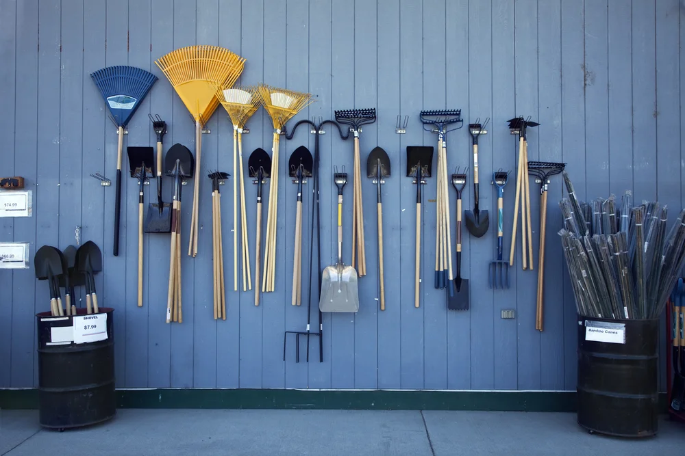 Rakes, shovels, and hoes hanging on a wall
